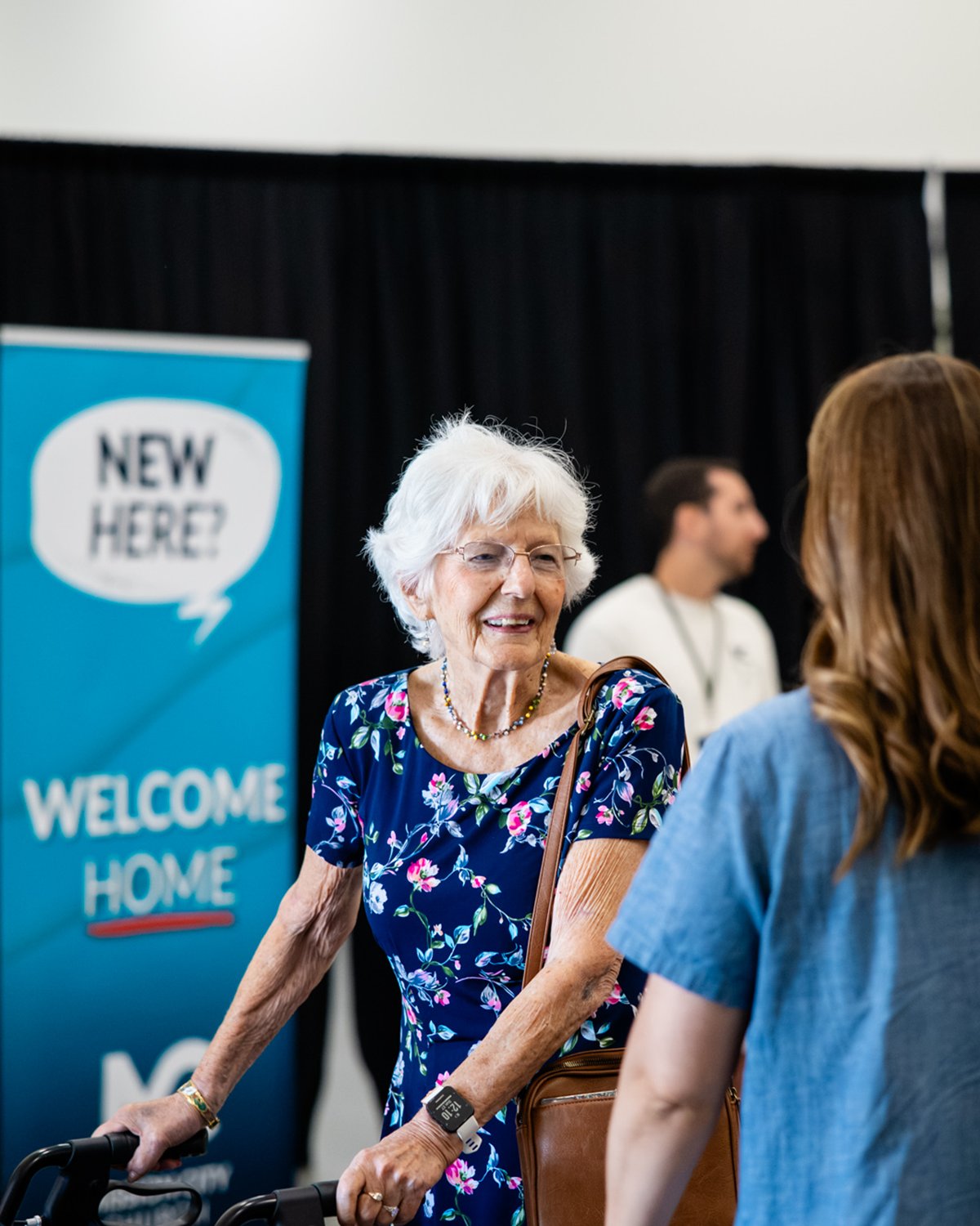 A smiling guest being welcomed at the New Here table